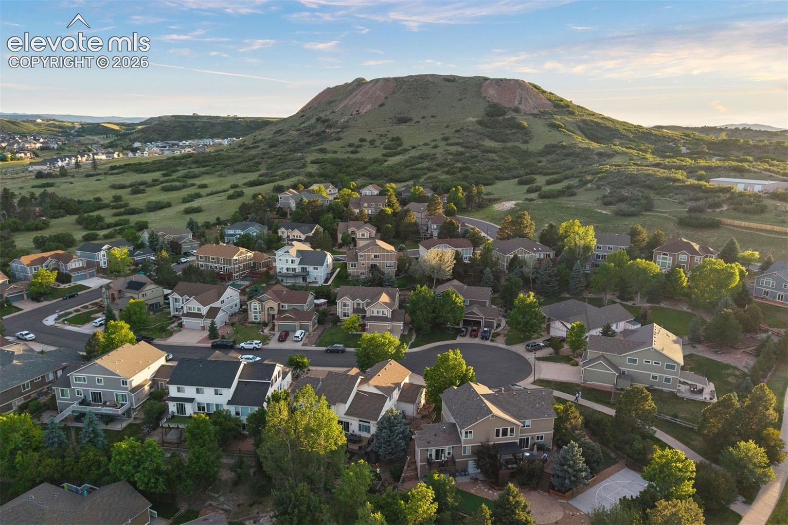 Residential neighborhood with a variety of architectural styles, surrounded by natural hillsides and abundant mature trees
