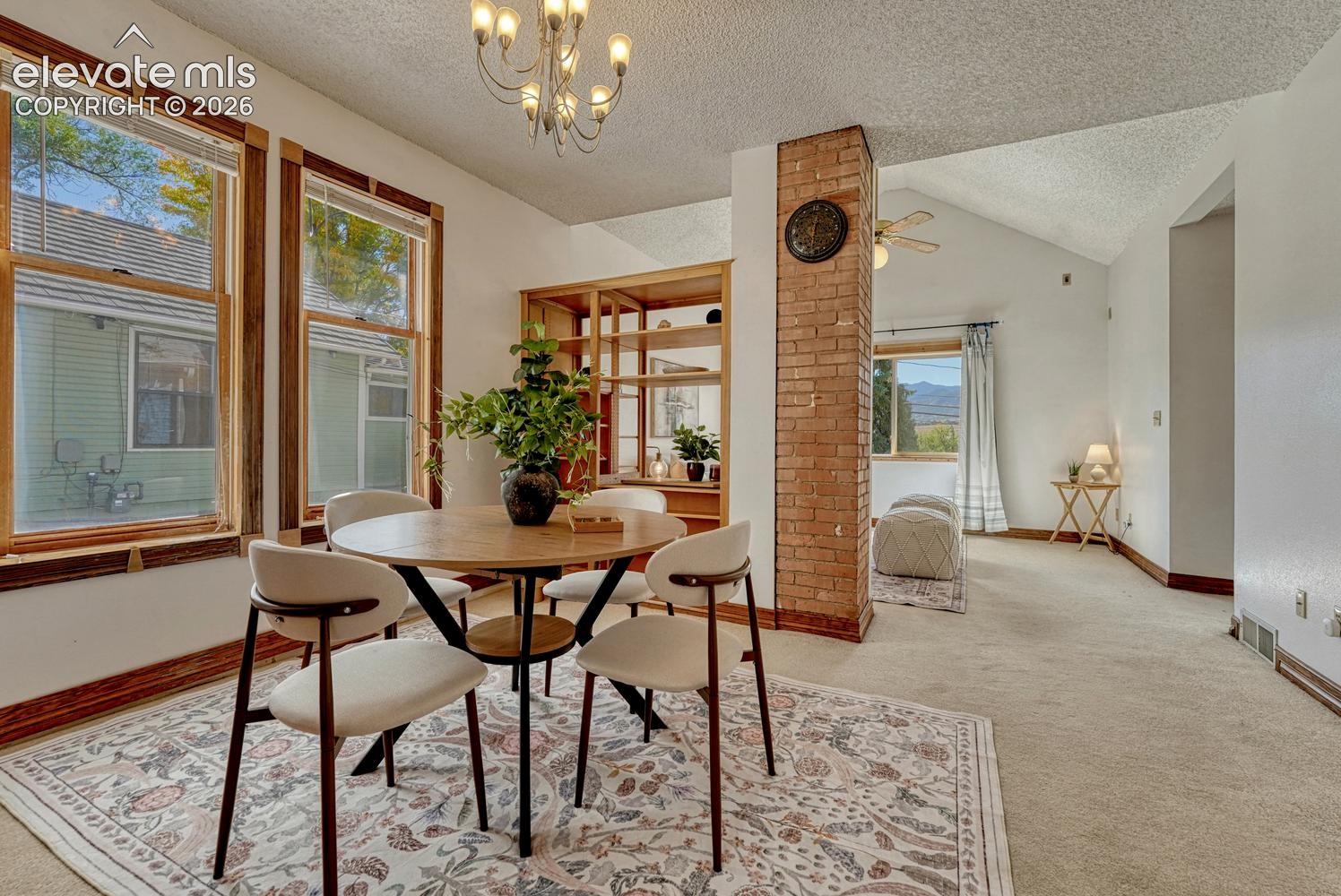 Integrated living space featuring multiple windows with wood trim, a brick-clad partial wall, and a wood-finish built-in shelving unit