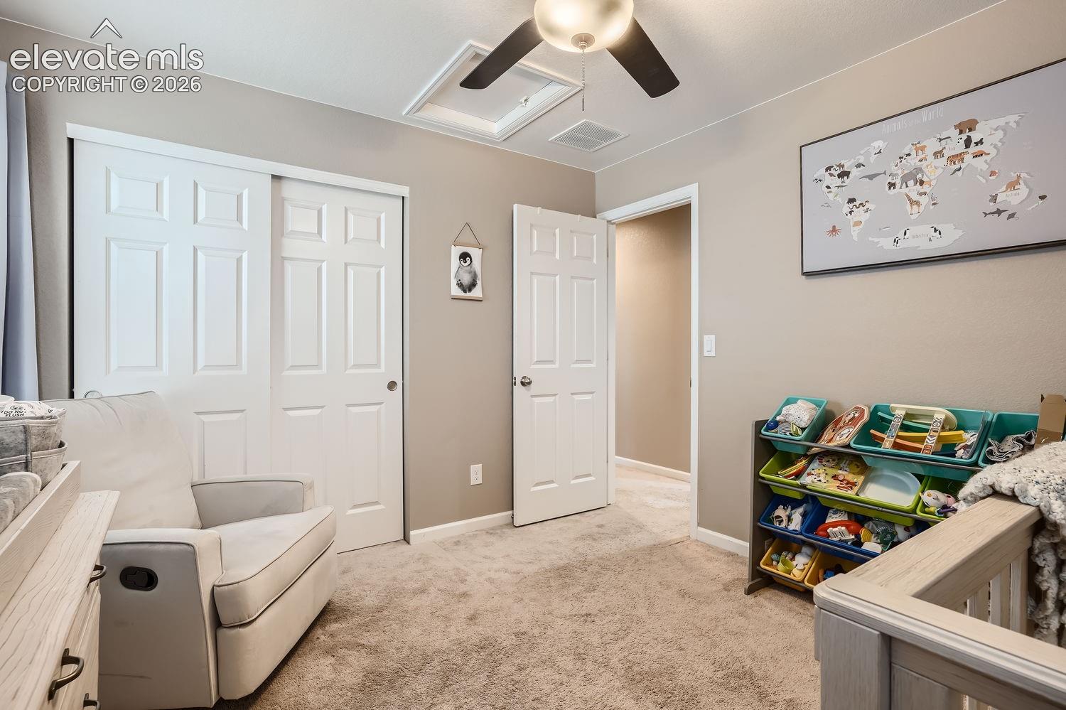 Room featuring neutral wall tones, wall-to-wall carpeting, a multi-panel sliding closet, a matching interior door, and a ceiling fan with integrated lighting