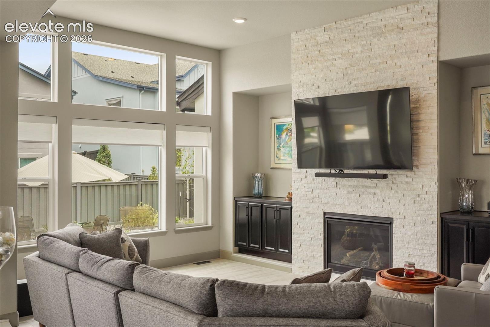 Living area featuring a floor-to-ceiling accent wall with stacked stone, an integrated fireplace, and built-in cabinetry