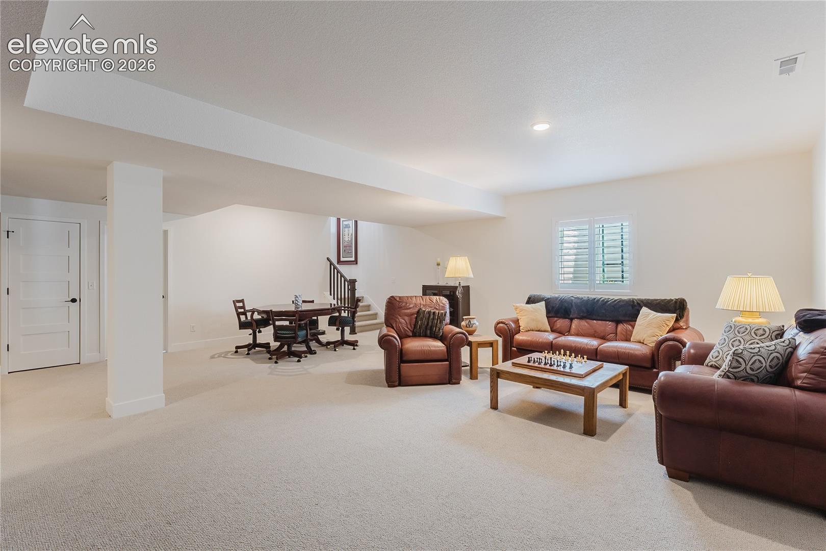 Recessed ceiling lighting, white interior doors, and a staircase with dark wood railings