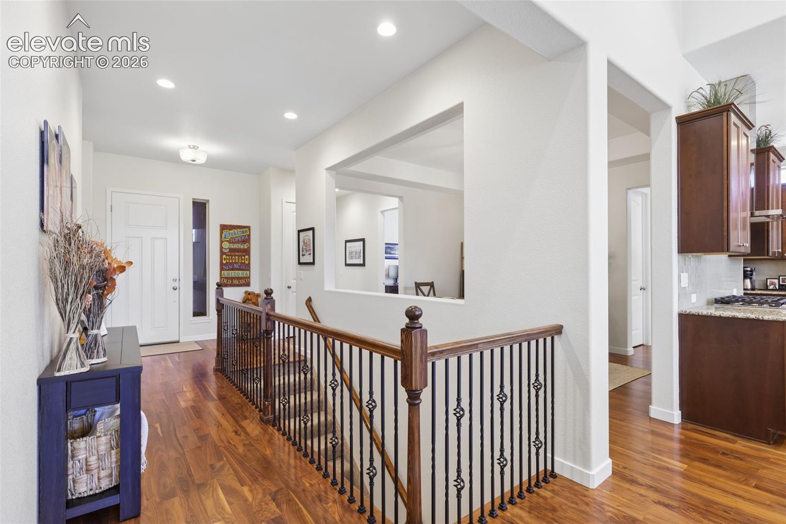 Hardwood-finish flooring throughout, featuring a staircase with wrought iron balusters and wood handrails