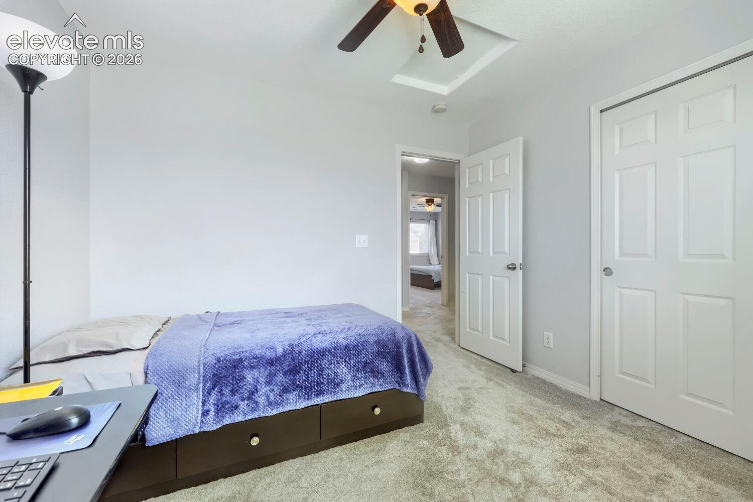 Room featuring neutral wall tones, wall-to-wall carpeting, a multi-panel interior door, and a ceiling fan with integrated lighting