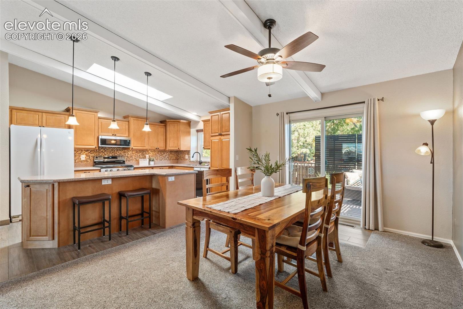 Open-concept kitchen featuring wood cabinetry, a breakfast bar, recessed lighting, a skylight, and sliding glass doors