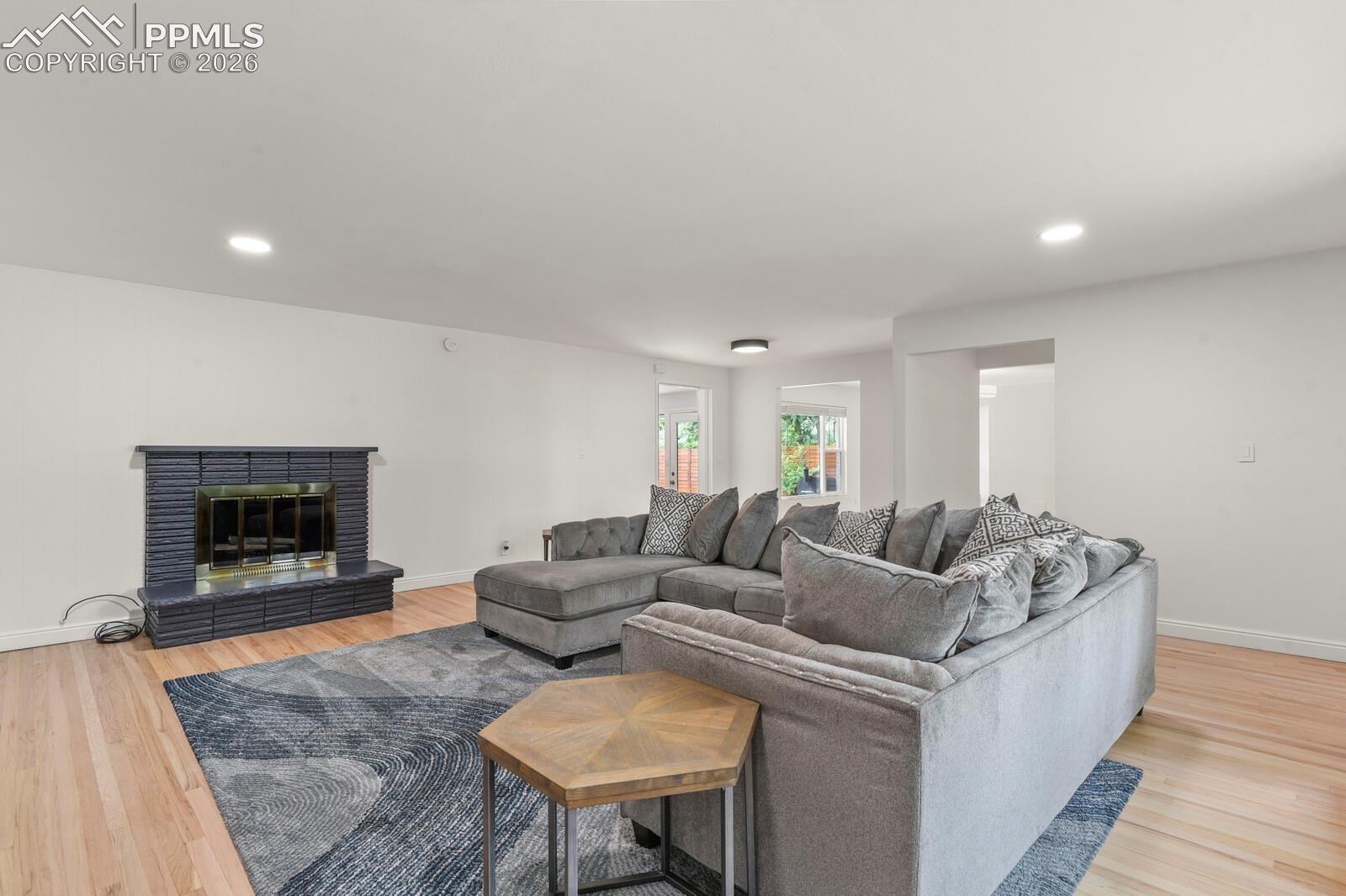 Hardwood flooring complements the  fireplace featuring a dark brick surround and hearth