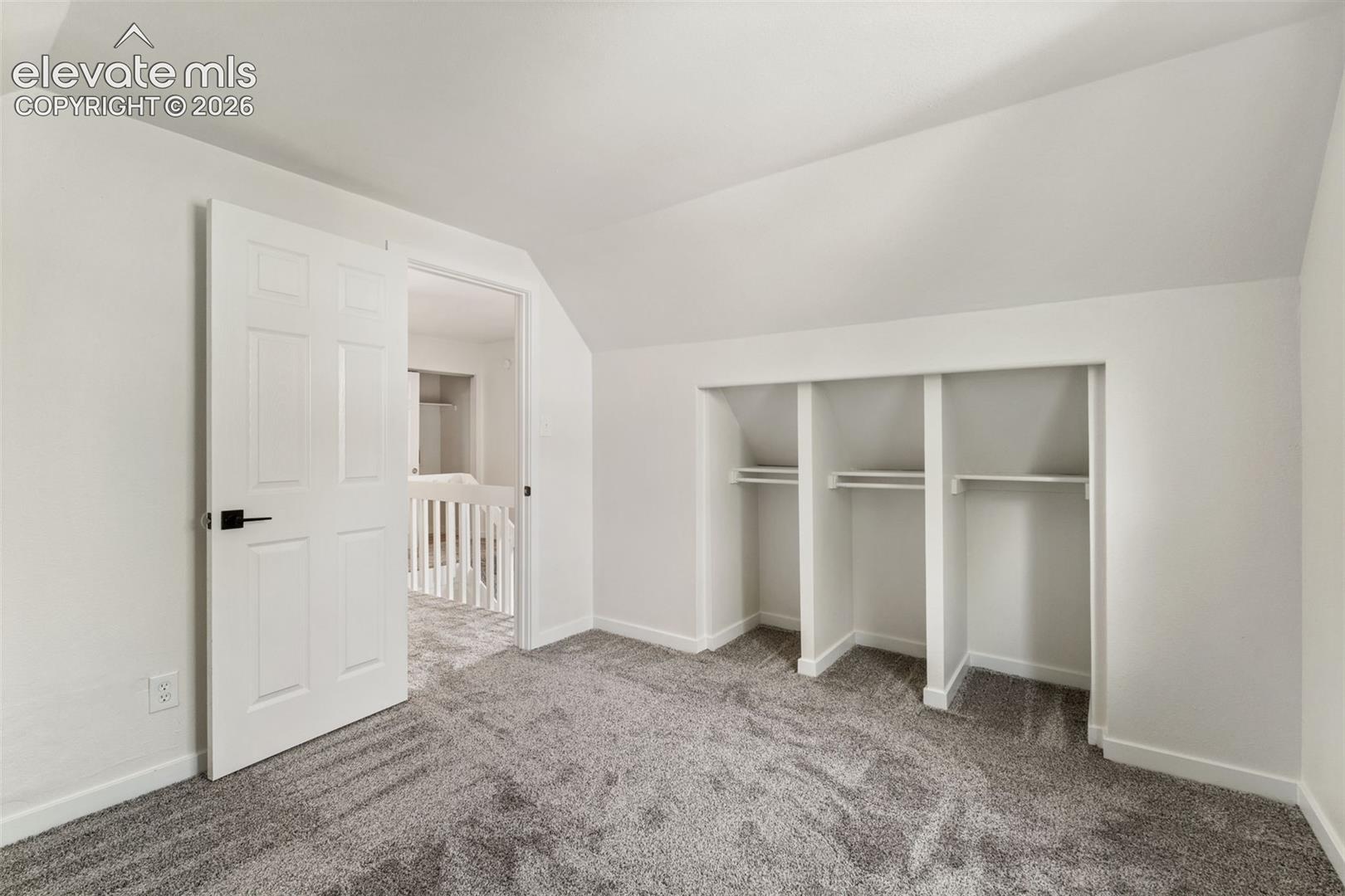 Sloped ceilings, wall-to-wall carpeting, and integrated triple-bay shelving featuring built-in hanging rods