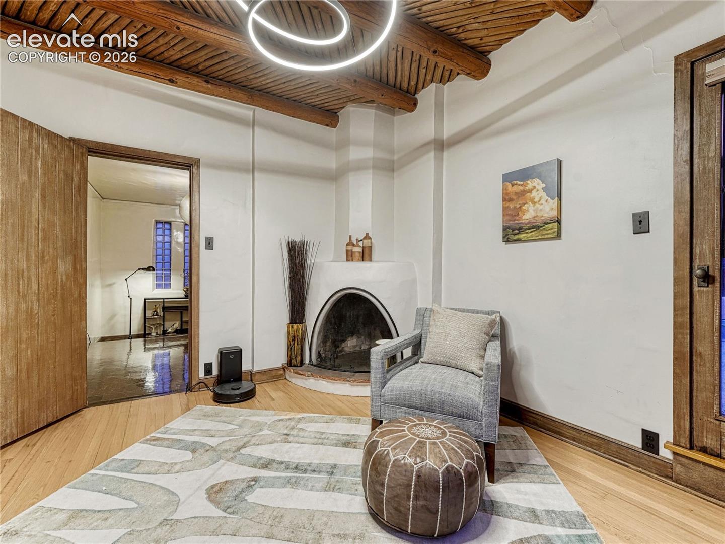 Primary Suite sitting room w/Kiva fireplace & Vigas ceiling.