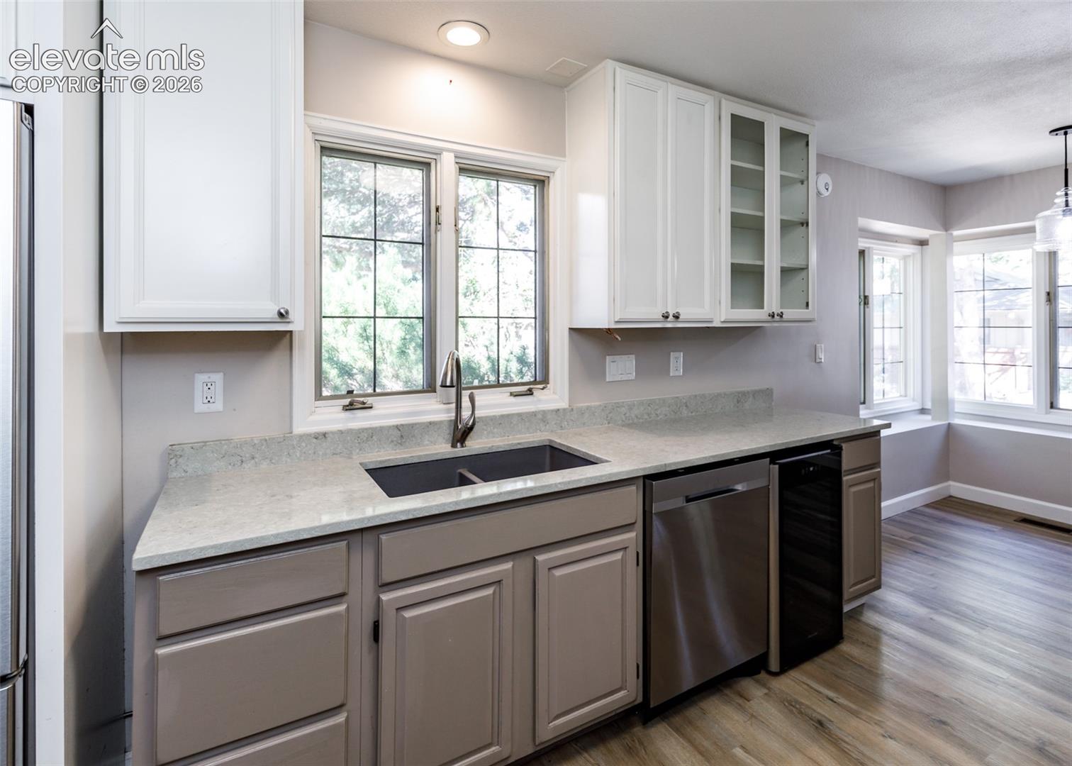 Kitchen featuring white upper cabinetry, grey lower cabinetry, light-colored countertops, and stainless steel appliances