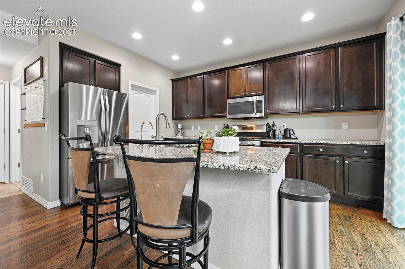 Recessed lighting keeps every corner of this kitchen bright, and the cabinetry is augmented by a full pantry through the door by the fridge.