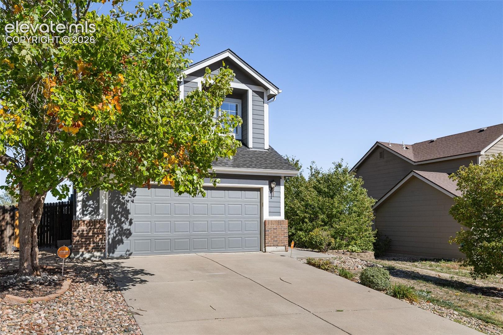 Two-story exterior featuring grey lap siding, a front-facing attached two-car garage, and masonry accents at the base