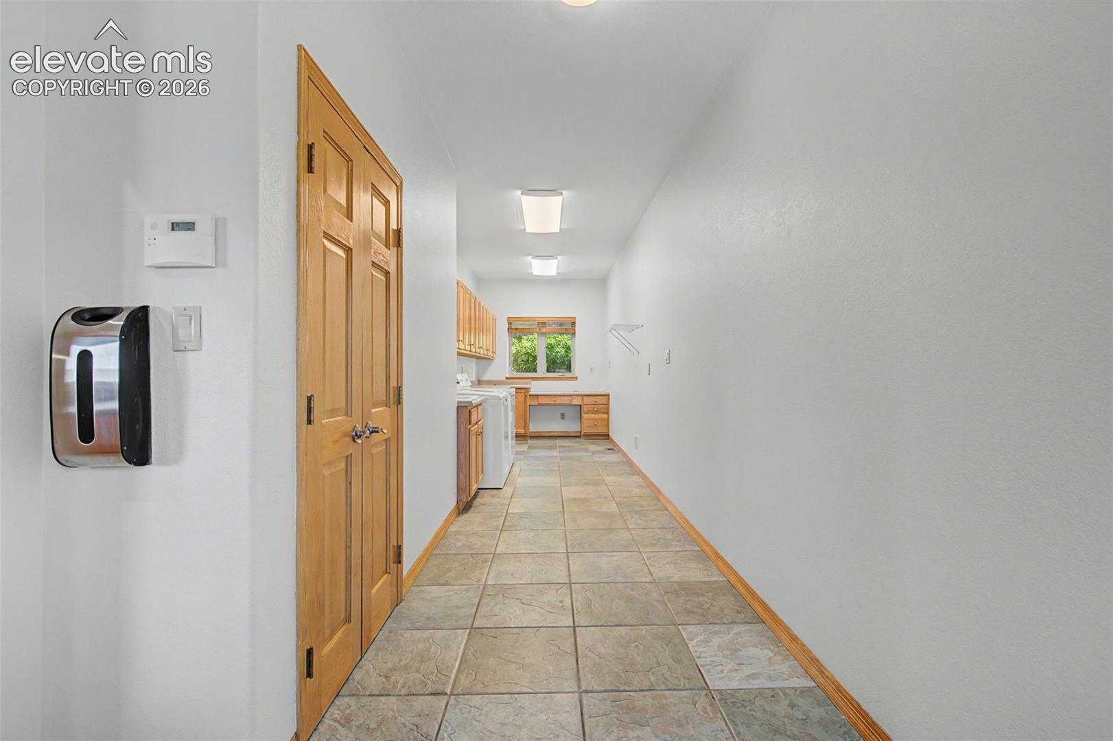 Utility room with tiled flooring, wood-finish cabinetry, and a built-in workstation
