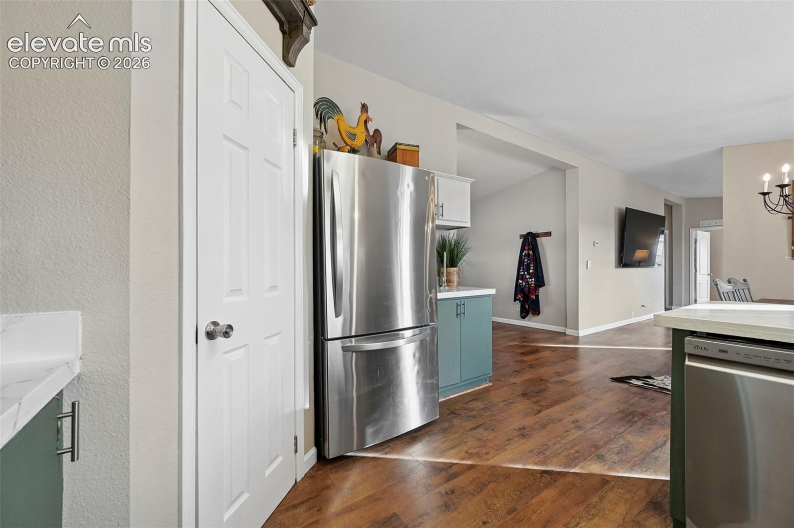 Kitchen featuring stainless steel refrigerator and dishwasher, wood-finish flooring, solid-surface countertops, and painted cabinetry with metal pulls