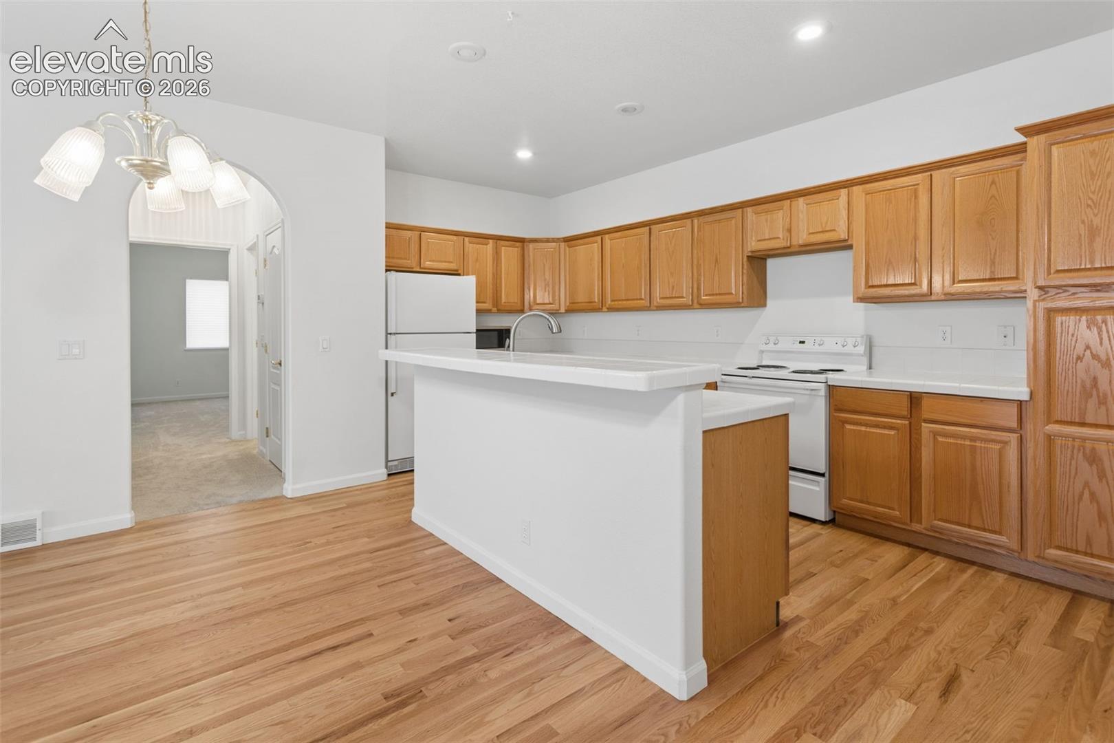 Open kitchen with island, tons of storage and freshly refinished hardwood flooring