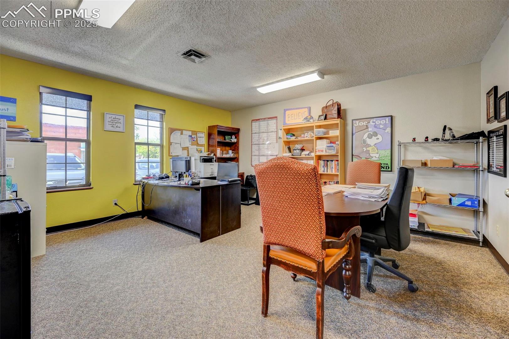 Carpeted home office featuring a textured ceiling and baseboards