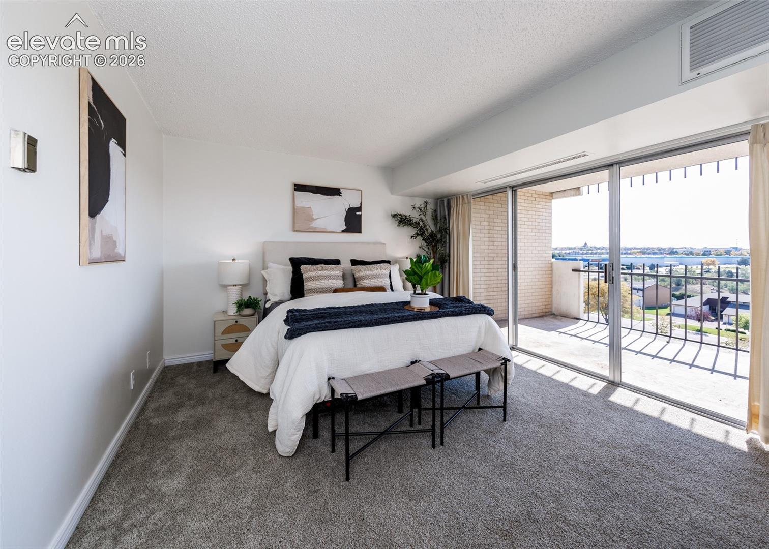 Bedroom featuring wall-to-wall carpeting, floor-to-ceiling glass sliding doors, and a private balcony with metal railing