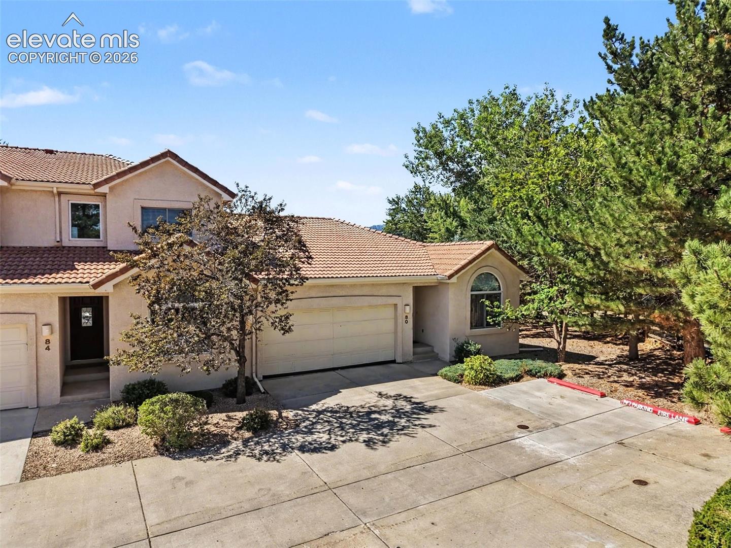 Stucco exterior with a tile roof, an arched window, and an attached garage