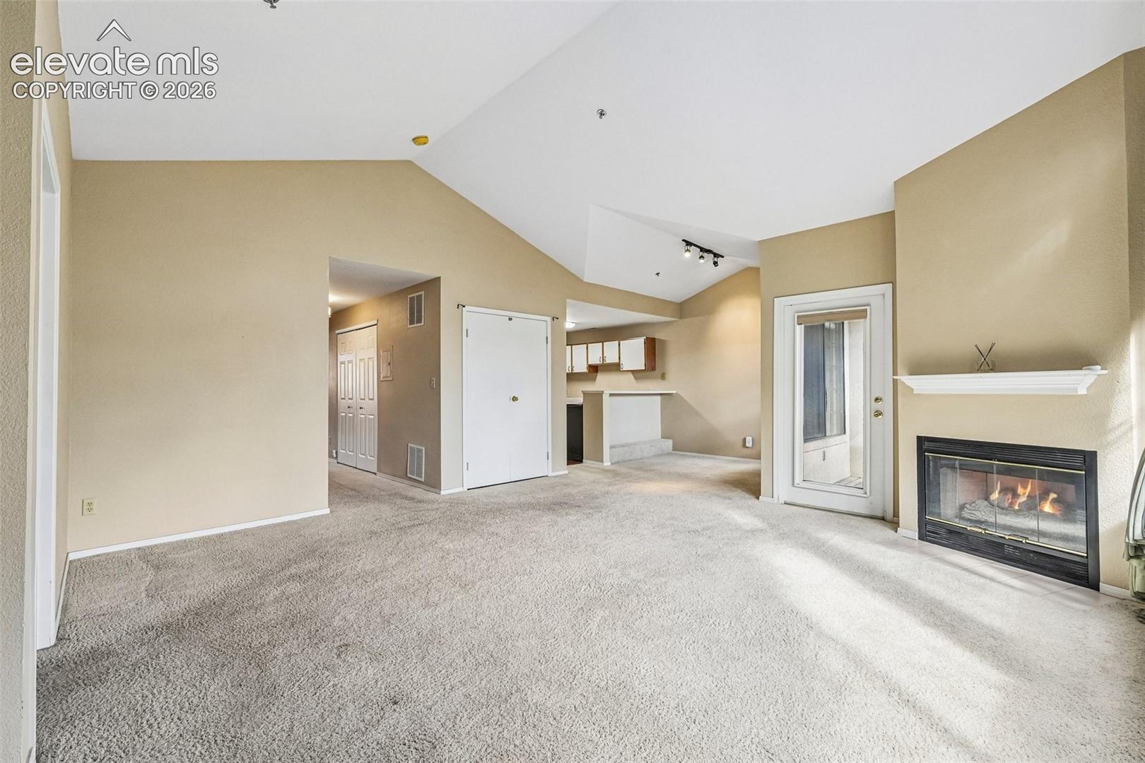 Living room with vaulted ceilings, a gas fireplace, a walk out and large windows brining in tons of natural light