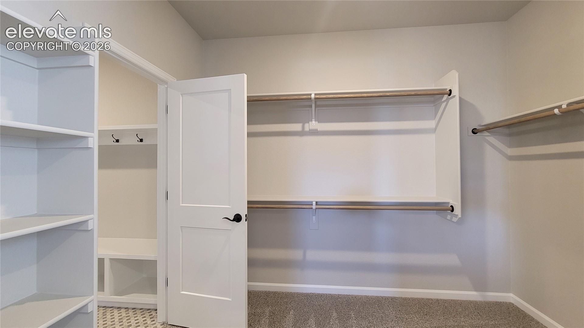 2 of 2 Primary walk-in closets with wood shelving and rods, conveniently attached to the laundry room! 