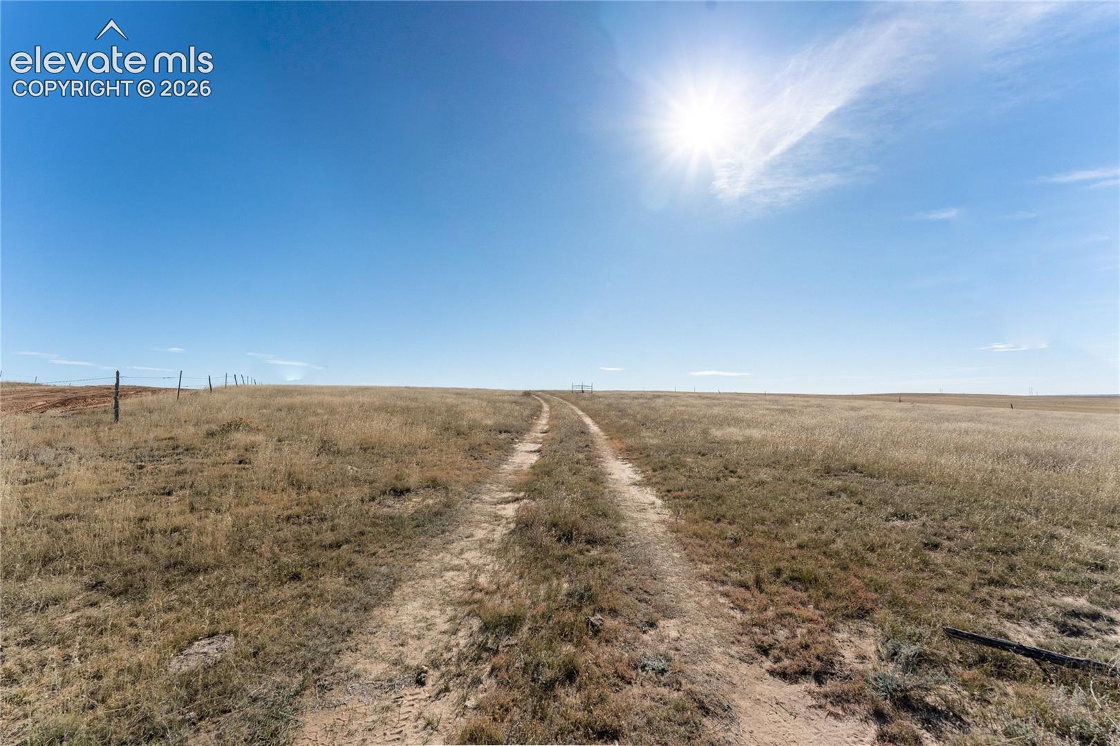 Expansive, level acreage featuring native grasses and perimeter fencing