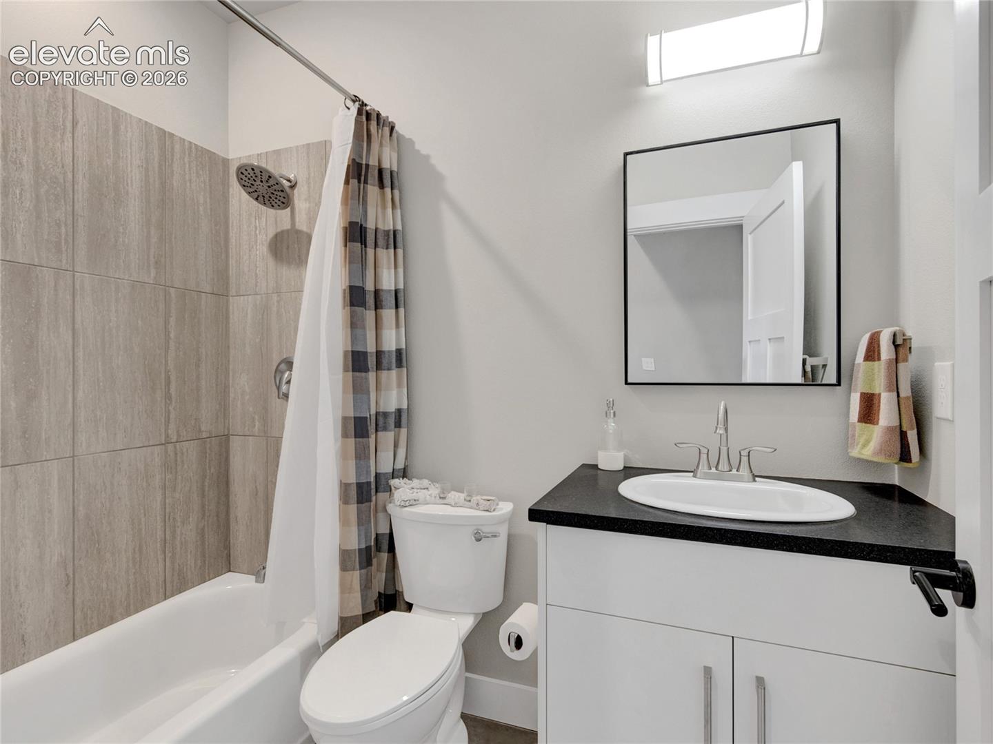 Bathroom featuring a white vanity with dark countertop, undermount sink, and chrome fixtures