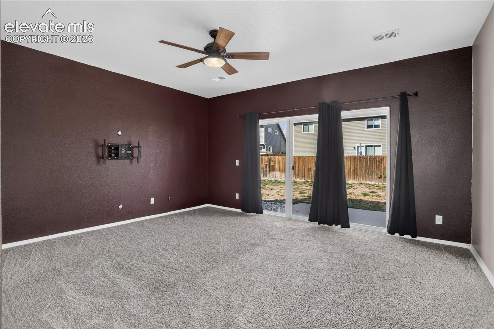 Spacious room featuring neutral carpeting, deep burgundy accent walls, and white ceiling trim