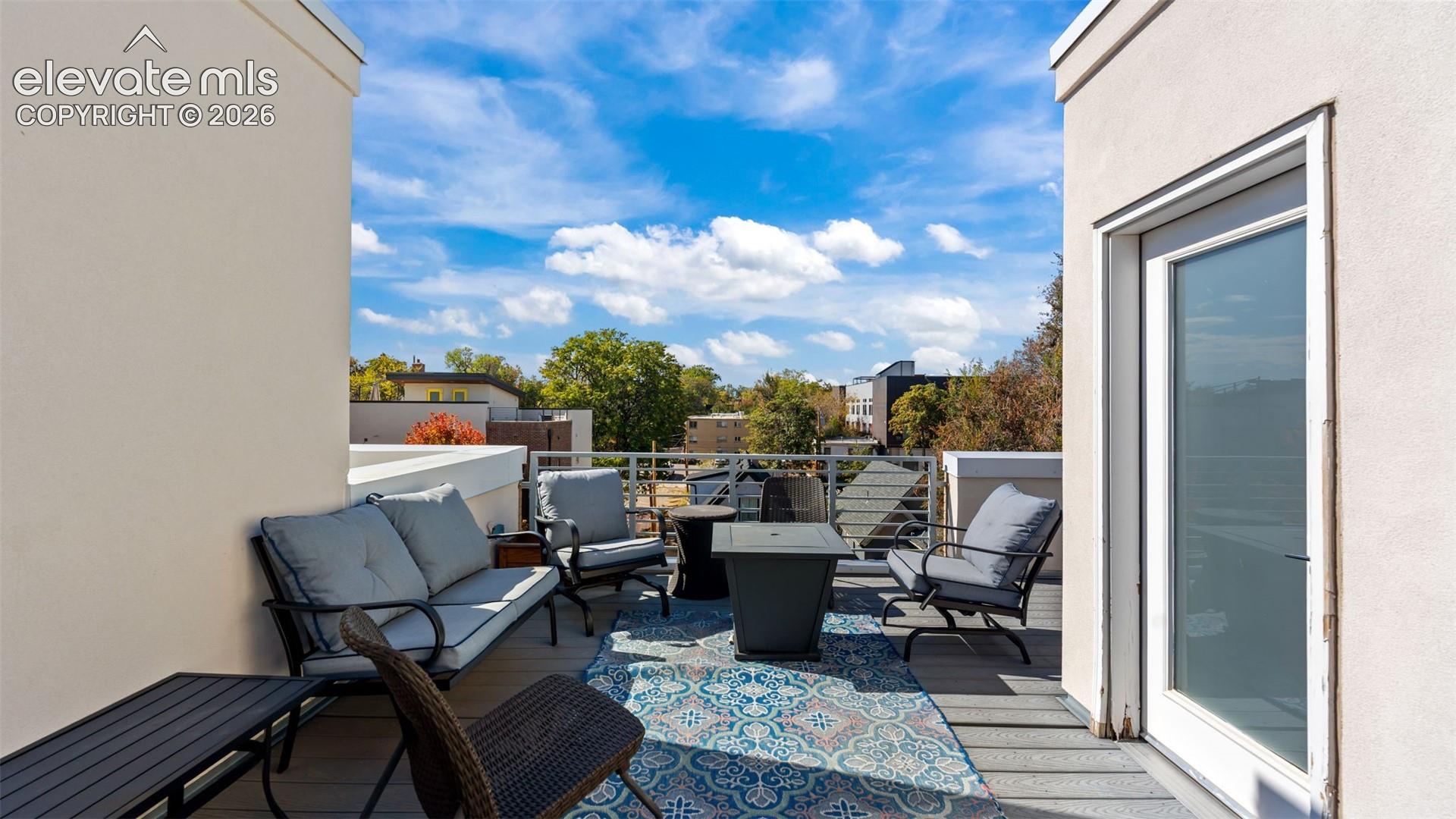 Rooftop terrace featuring composite decking, metal railing, and direct access via a glass-paneled door