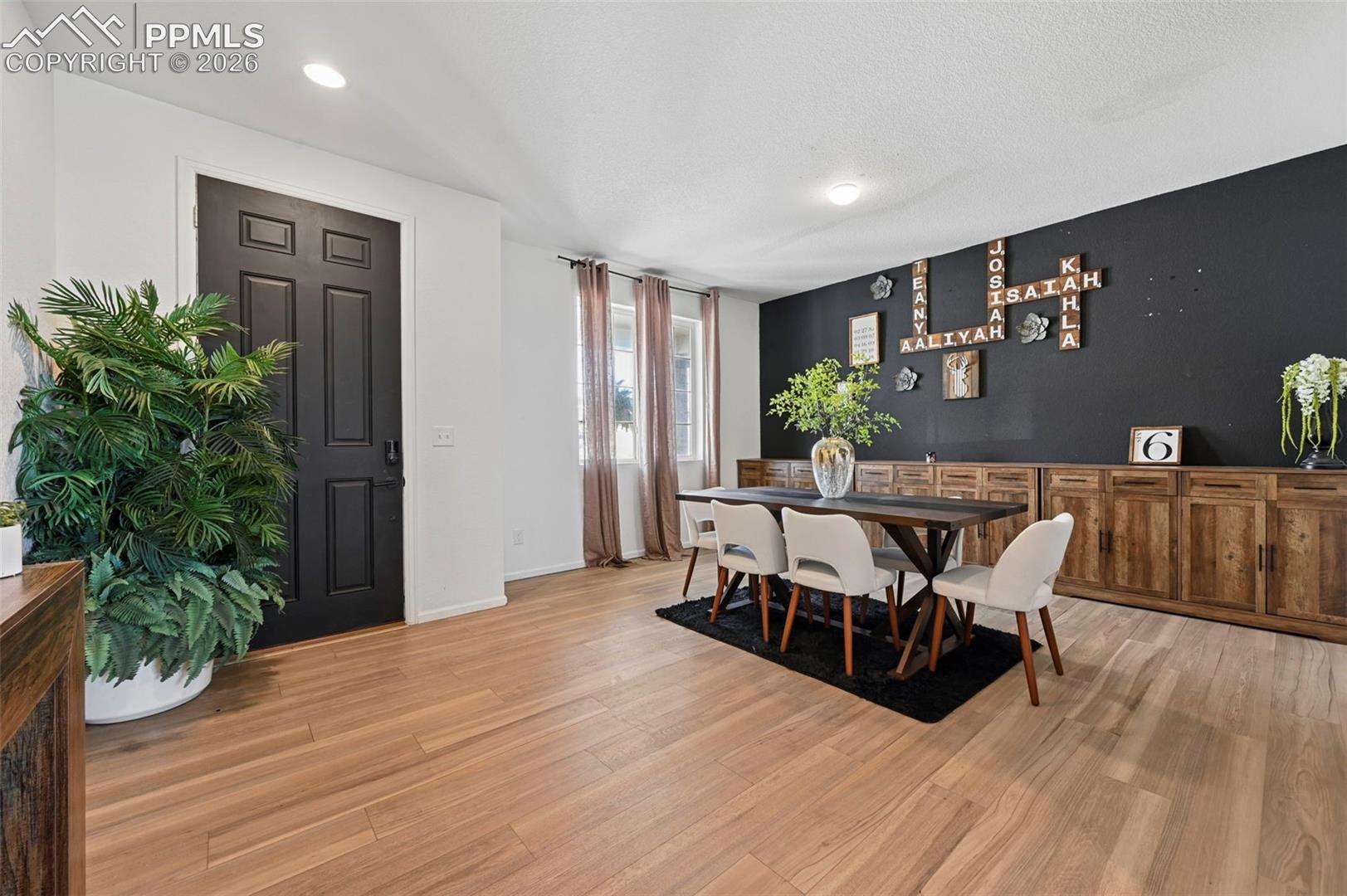 Open-concept living area featuring light wood-finish flooring, recessed lighting, and a dark accent wall