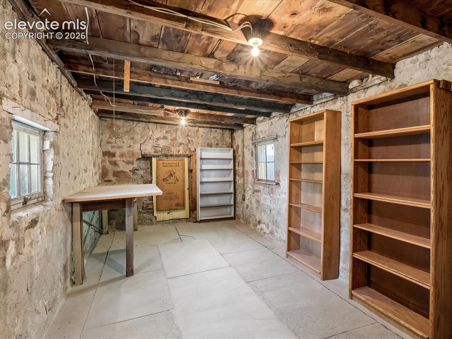 Exposed wood-beam ceiling, stone walls, and concrete flooring define this space