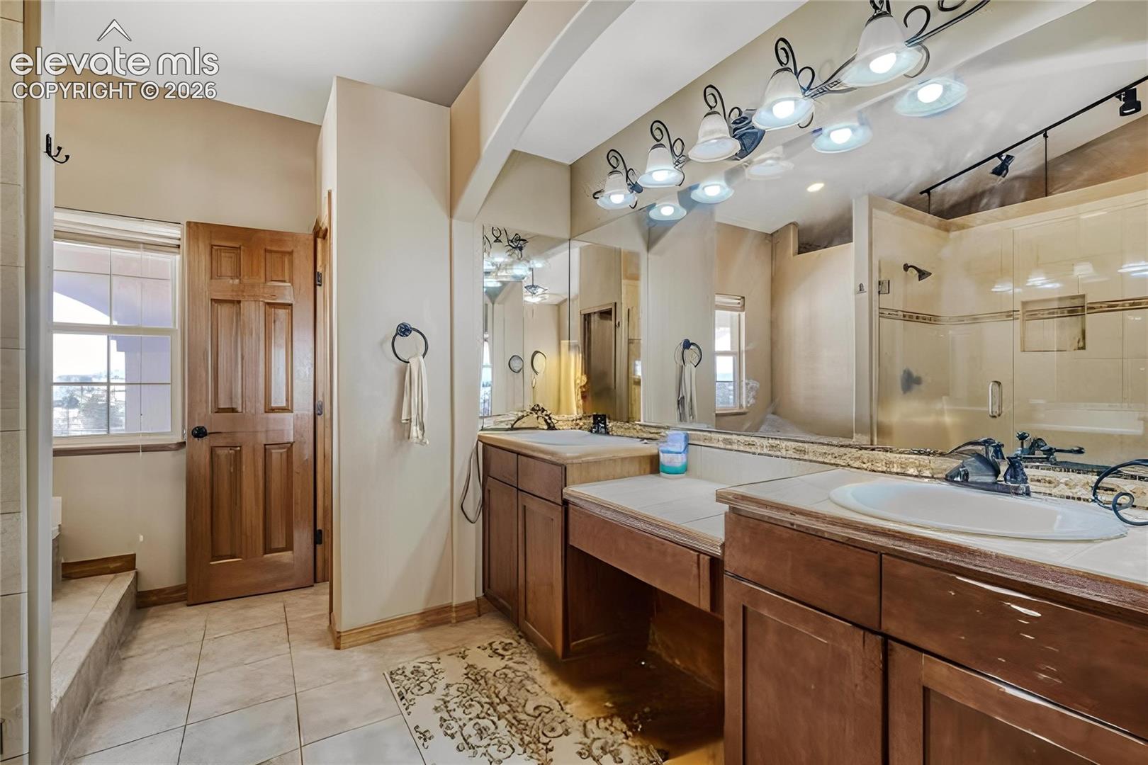 Bathroom featuring a dual vanity with integrated sinks, tile countertops, and dark wood-finish cabinetry