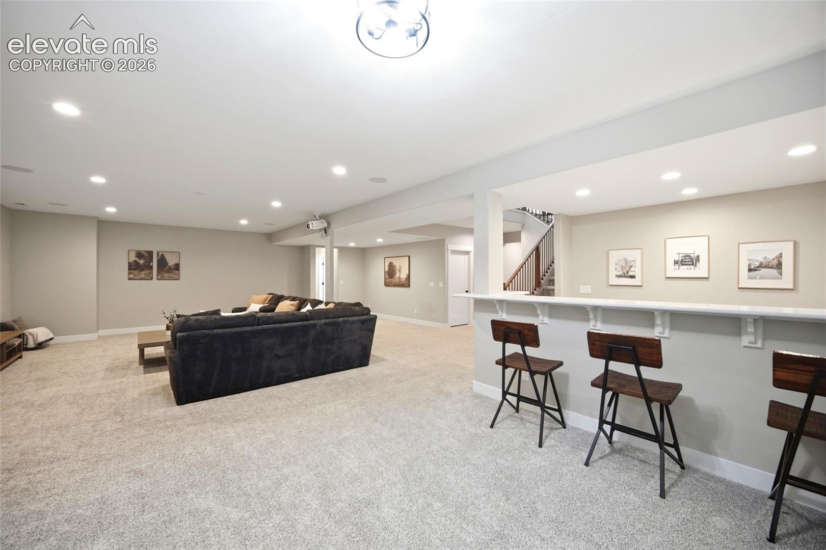Open-concept interior featuring recessed lighting, a built-in bar with a solid-surface countertop, and carpeted flooring