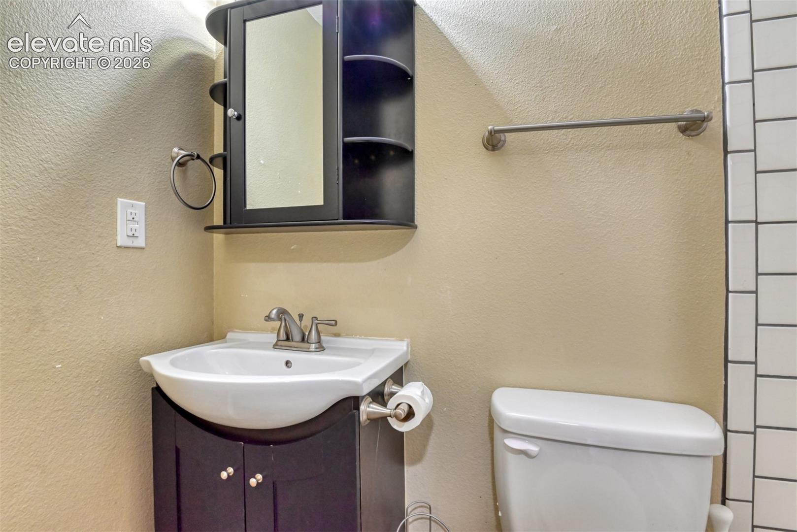 Bathroom featuring a dark wood-finish vanity with an integrated sink, brushed nickel faucet, and coordinating wall-mounted medicine cabinet