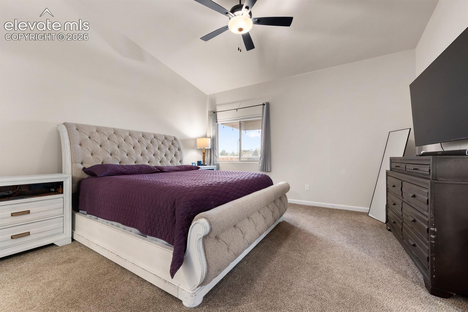Vaulted ceiling featuring a central lighted ceiling fan and neutral wall finishes
