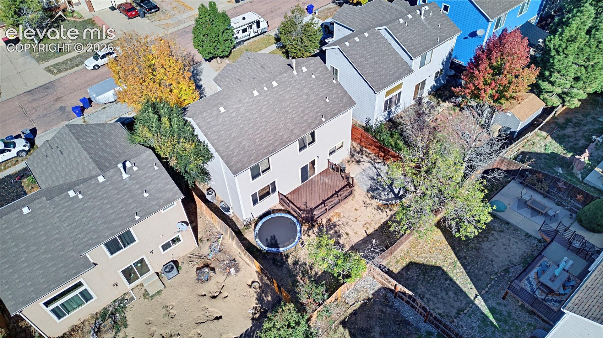 Aerial view of a two-story residence featuring an elevated wood deck and a fenced backyard