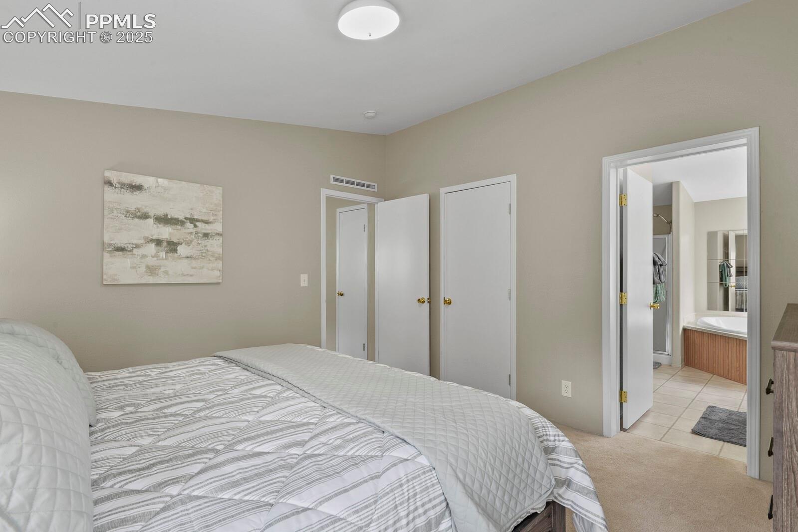 Carpeted bedroom with tile patterned flooring and ensuite bath