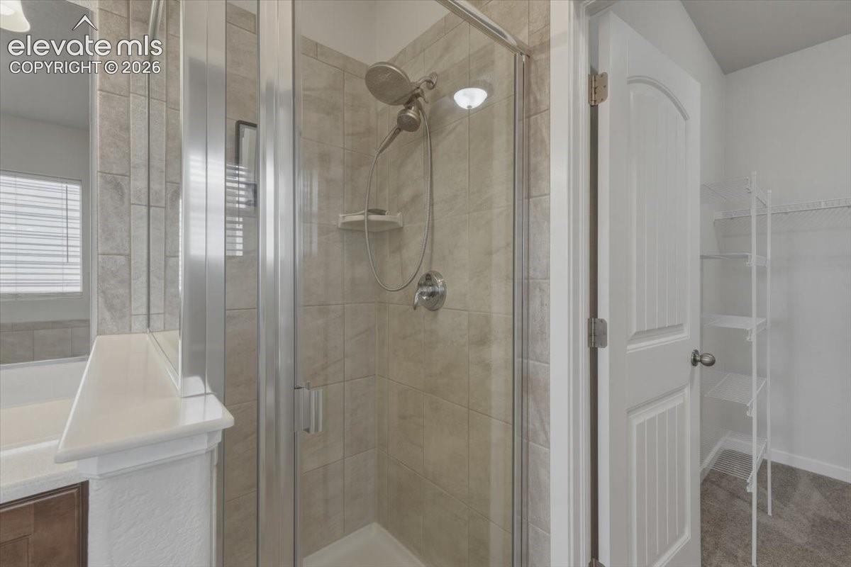Walk-in shower with clear glass enclosure and light-toned tile surround