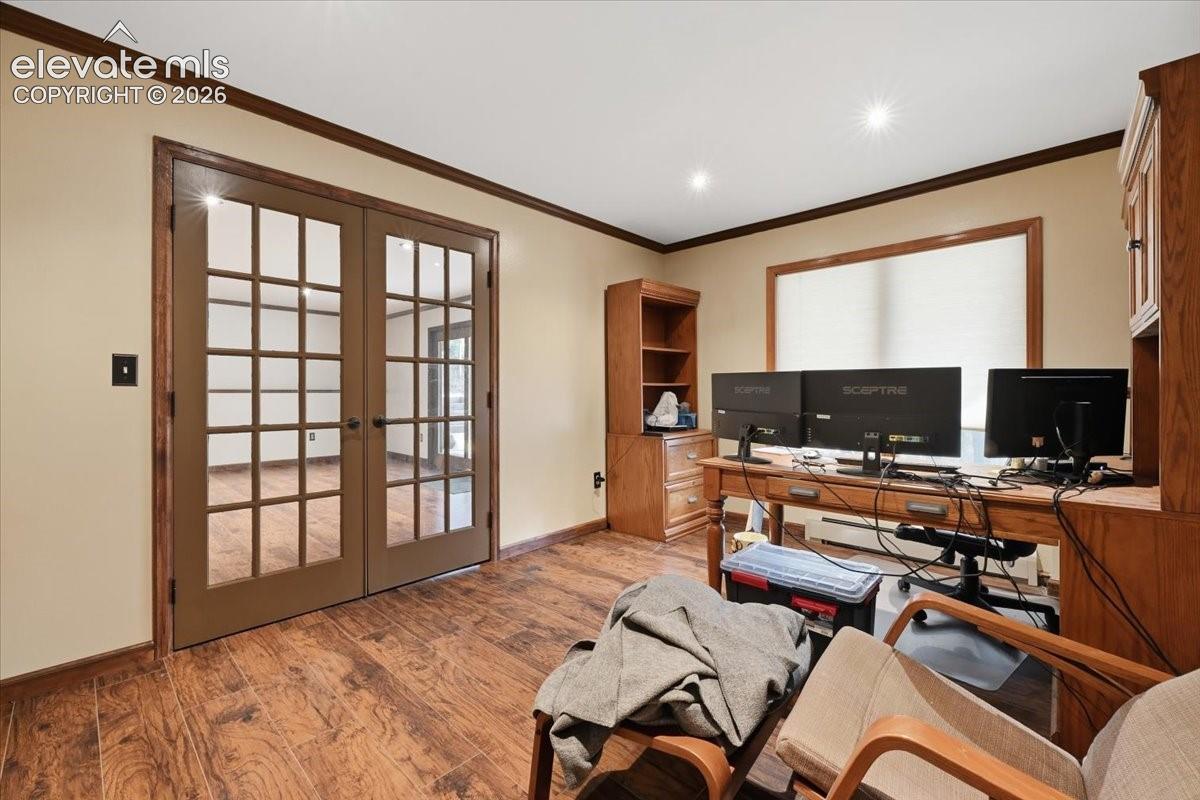 Wood-finish flooring with dark trim, recessed lighting, and a large window