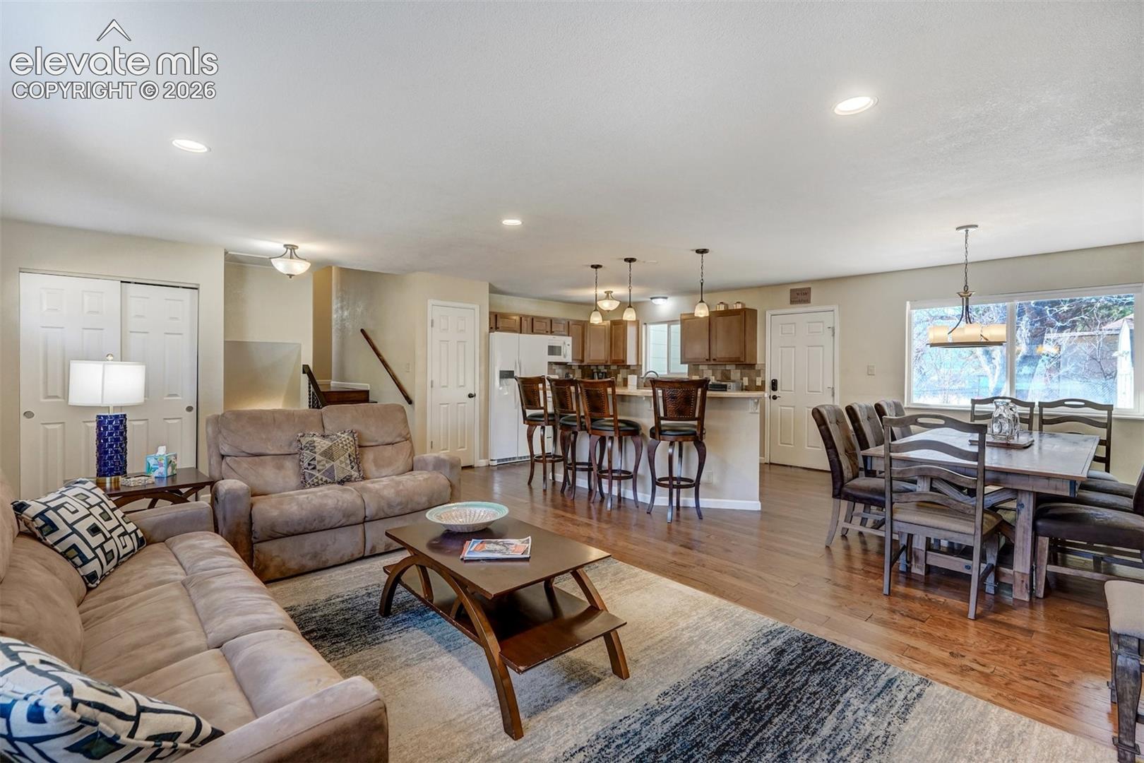 Hardwood flooring, recessed lighting, kitchen island with seating, pendant lighting, and dining area