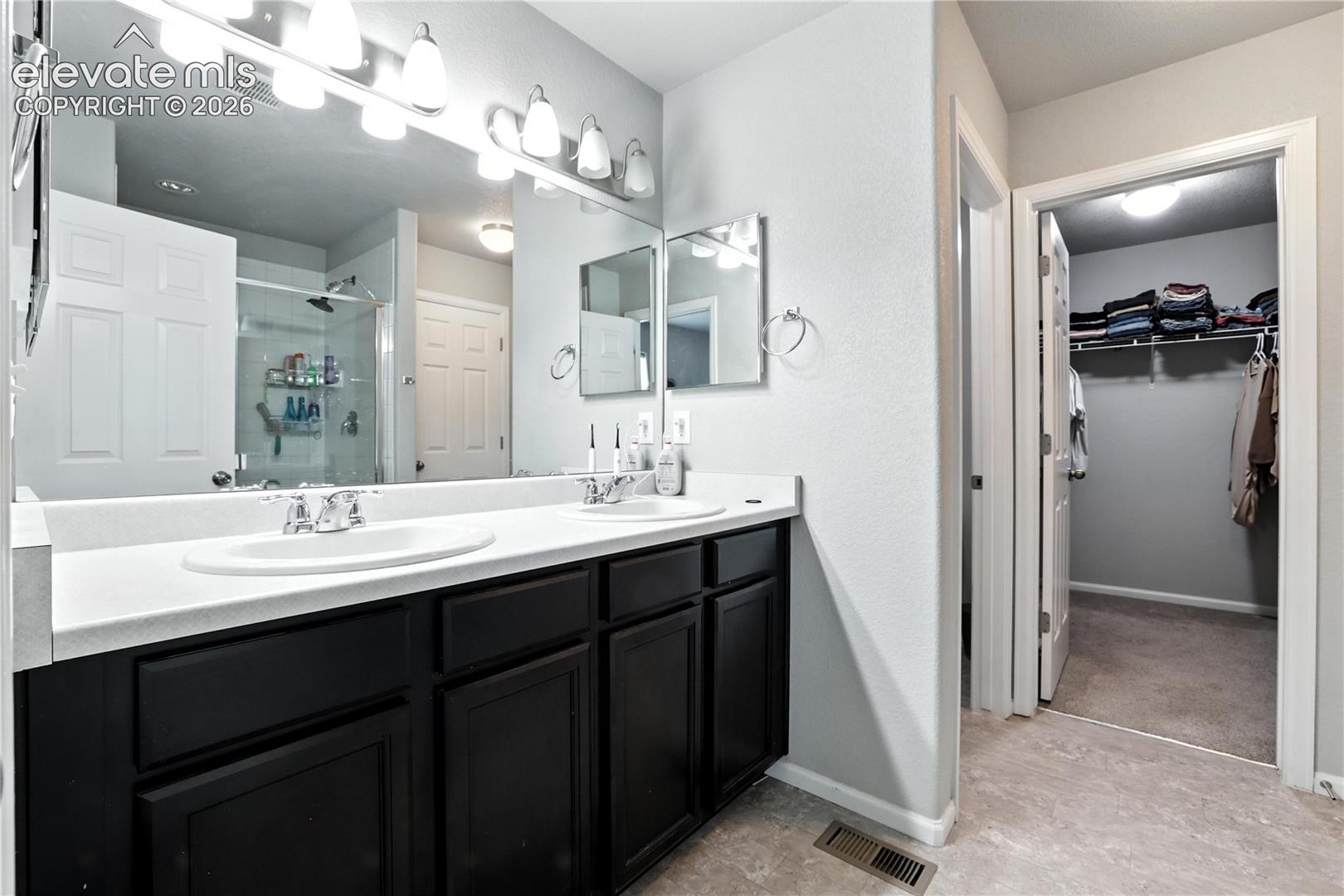 Double vanity with white countertops, dark wood-finish cabinetry, and polished chrome fixtures