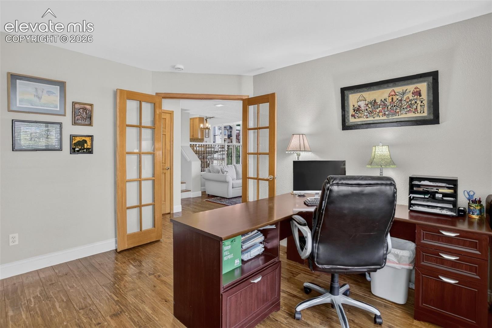 Office space featuring wood-finish flooring, light gray walls, and French doors