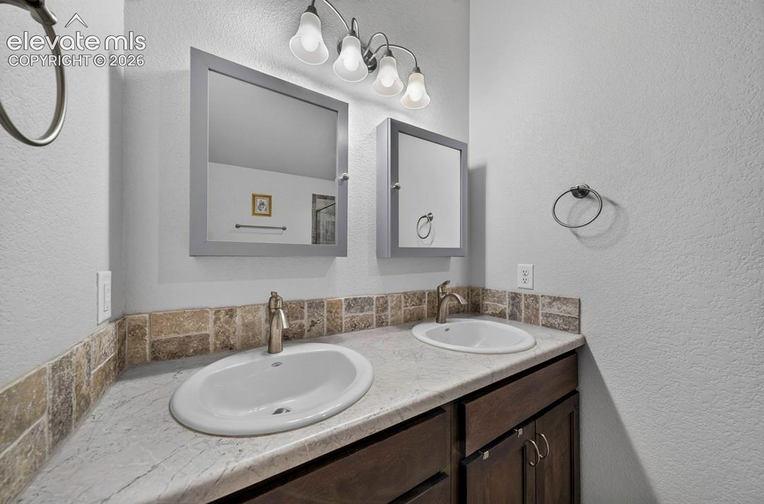Dual vanity featuring oval undermount sinks with brushed nickel single-handle faucets, set into a stone-finish countertop