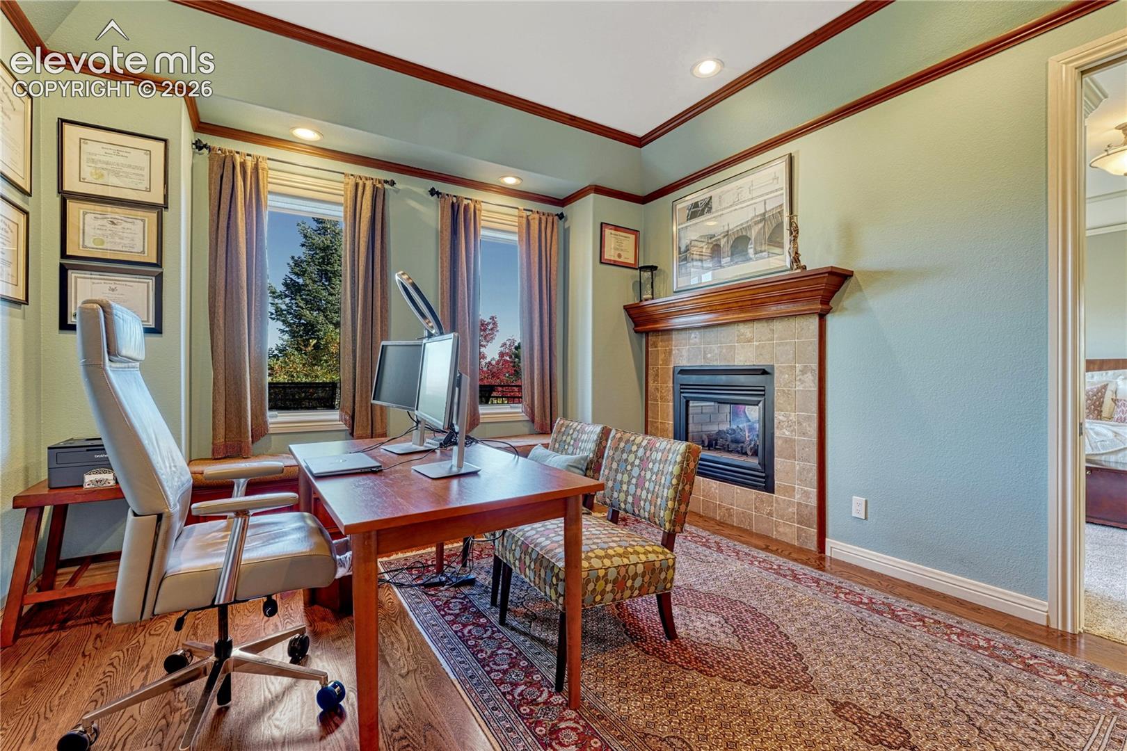 Room featuring a fireplace with a stone-tile surround and wood mantel, crown molding, recessed lighting, wood-finish flooring, and a built-in window bench