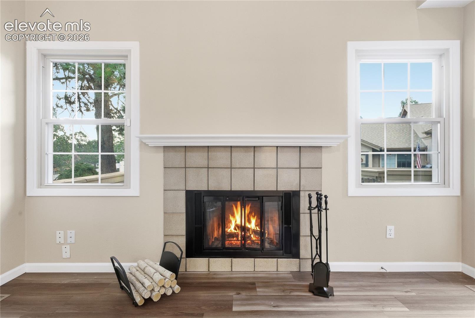 Fireplace with a tile surround and mantel, flanked by two windows
