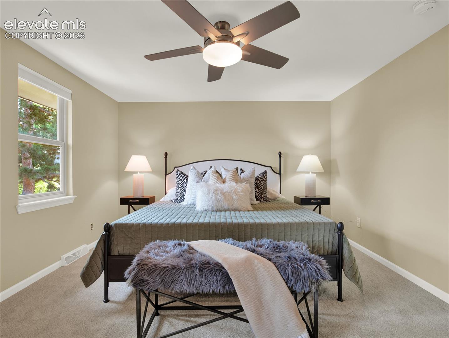 Neutral-toned walls, carpeting, and a central ceiling fan with integrated lighting