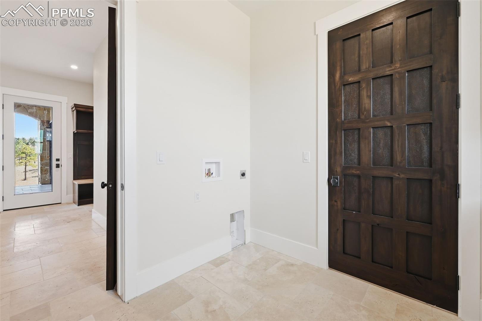 Laundry room featuring hookup for a washing machine, hookup for an electric dryer, recessed lighting, and light stone finish floors. View is to entry hallway.