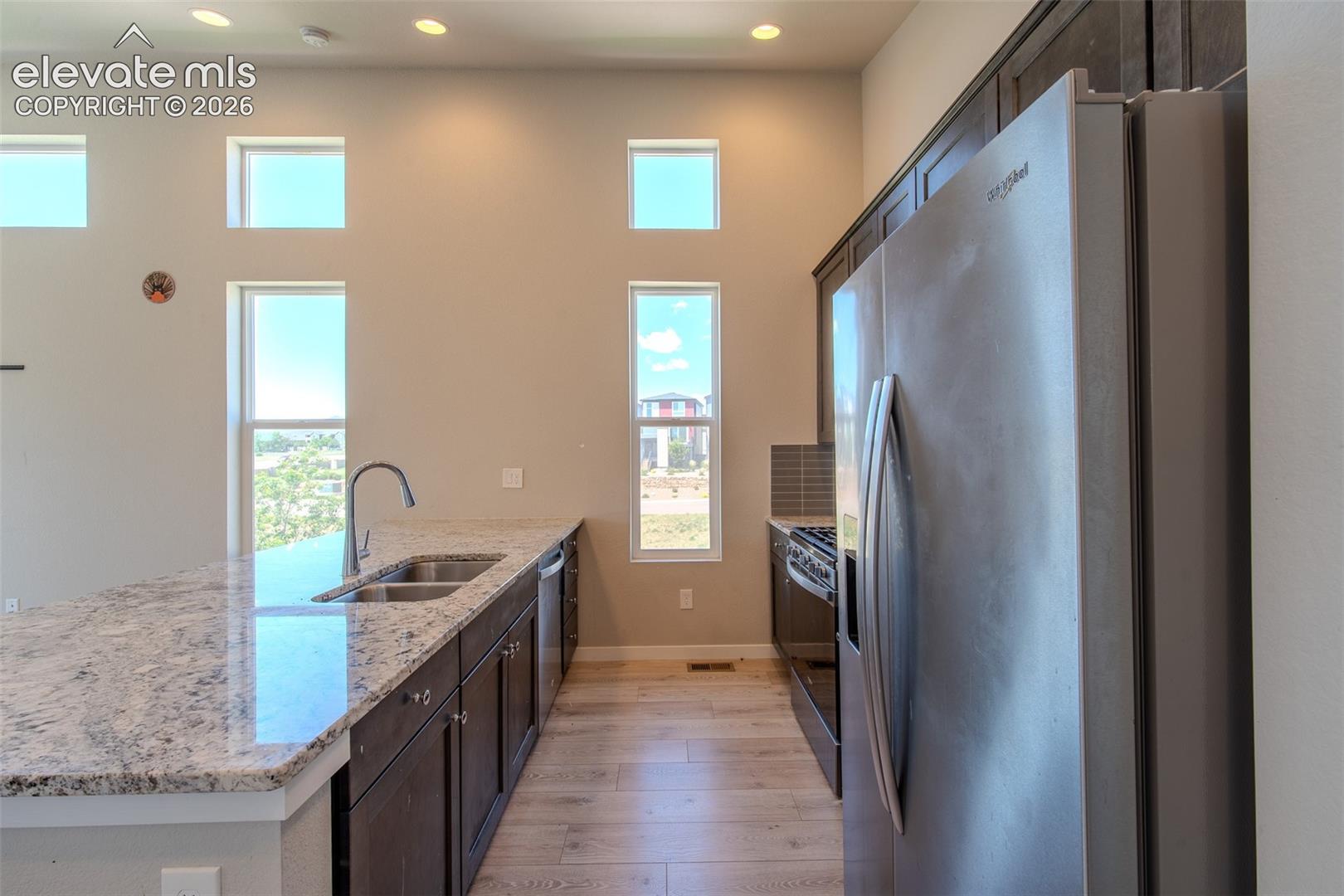 The Kitchen boasts a dual stainless steel sink, dishwasher, gas range oven, built-in microwave, and side by side refrigerator.