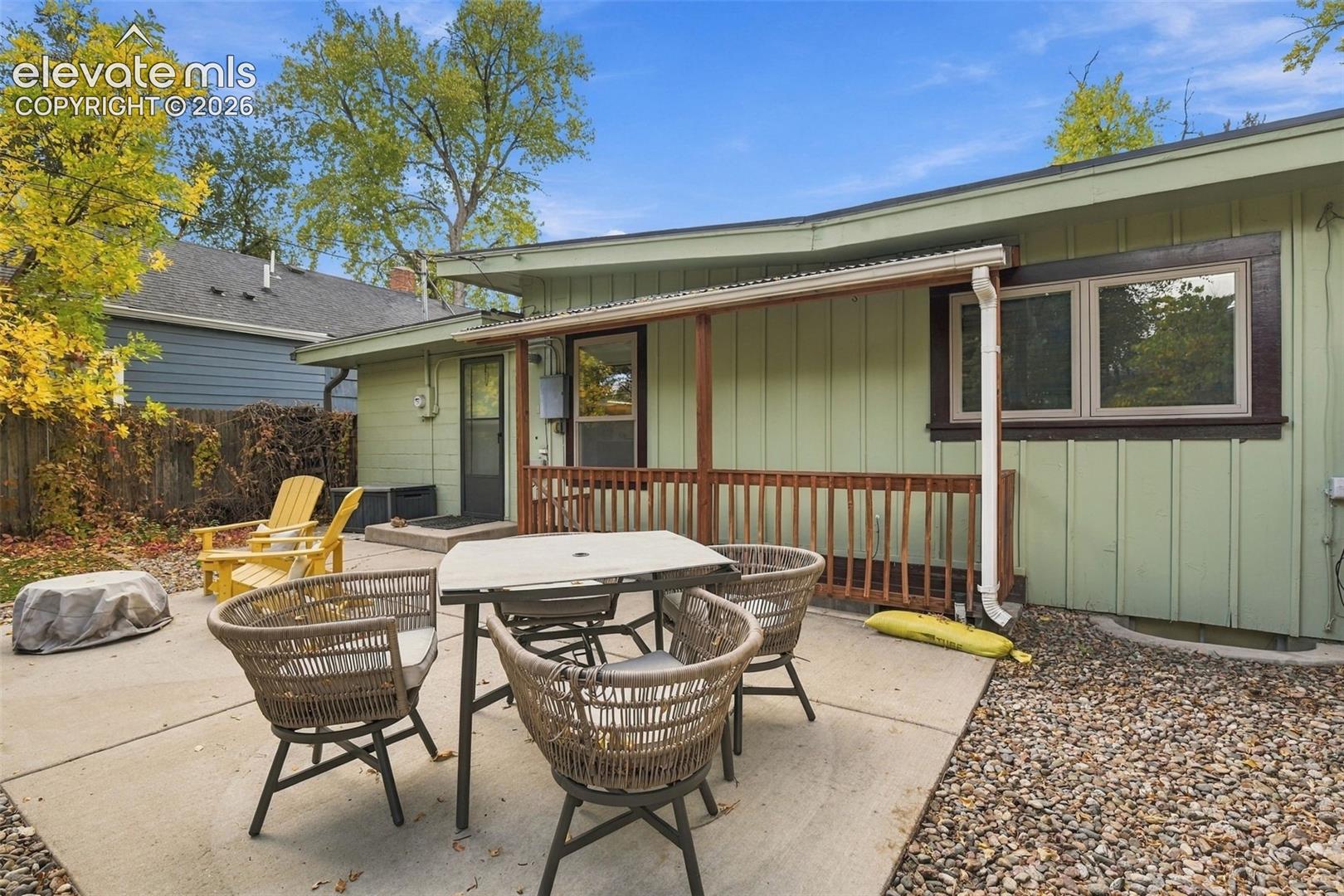 Exterior patio featuring a concrete slab surface, covered wood porch, vertical siding, and surrounding stone landscape