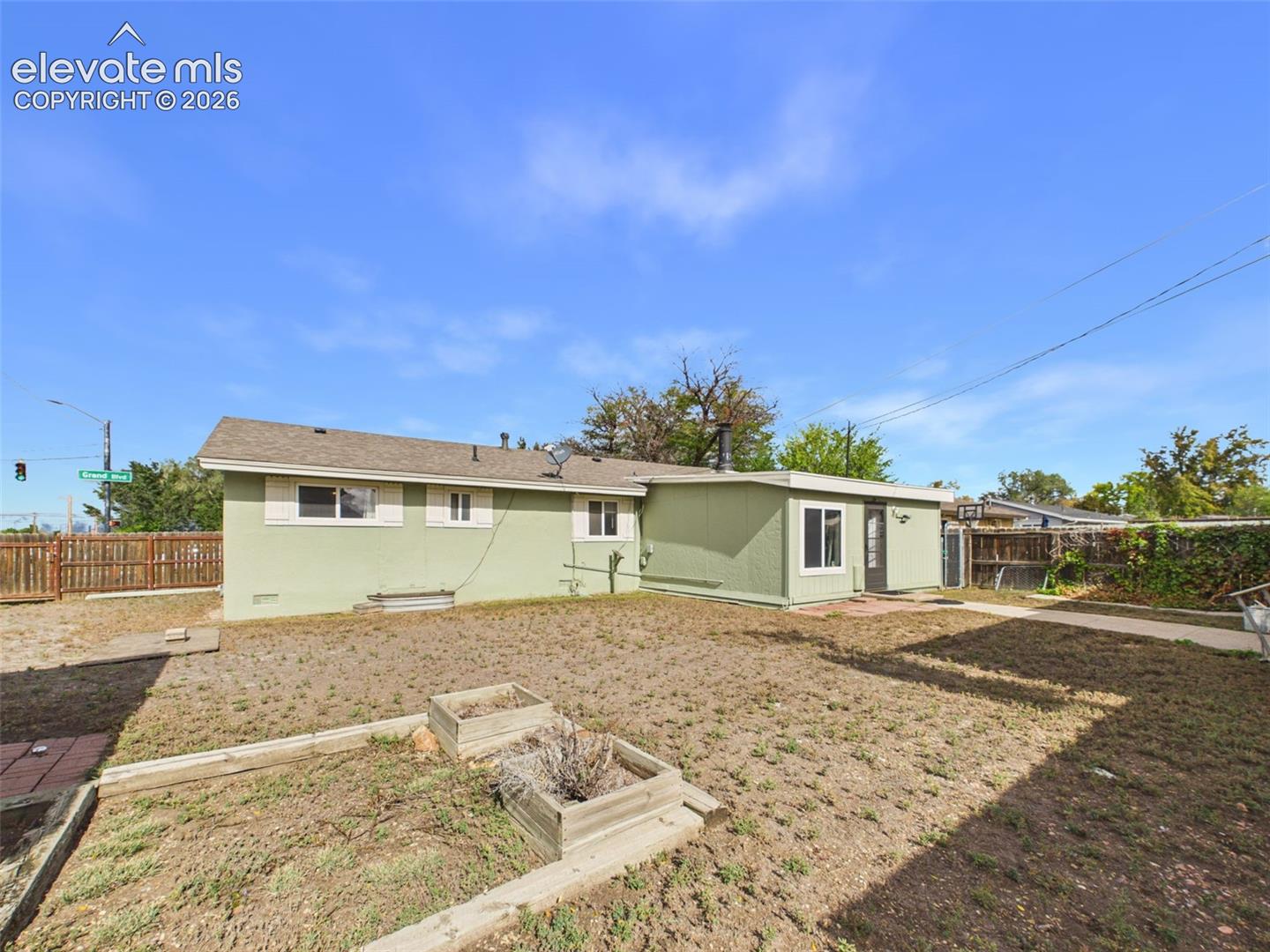 Additional backyard view showcasing the home's rear addition, concrete walkway, fenced yard, and separate enclosed outdoor structure.