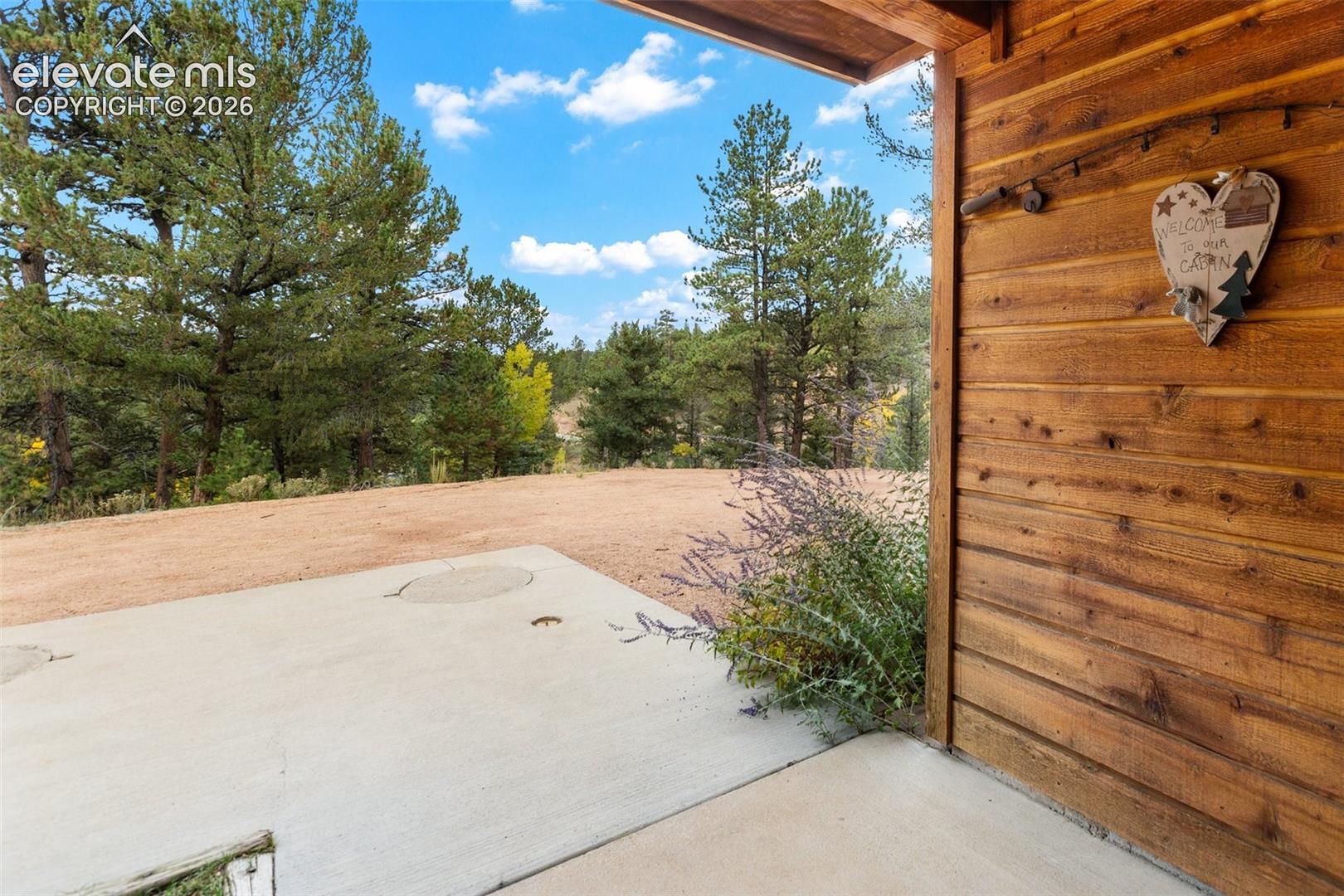Concrete patio with natural wood siding and expansive natural surroundings