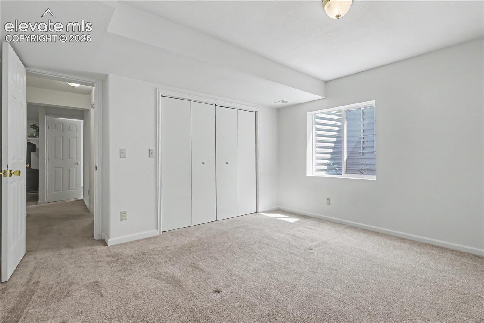 Spacious room featuring neutral carpeting, white walls, and a large window