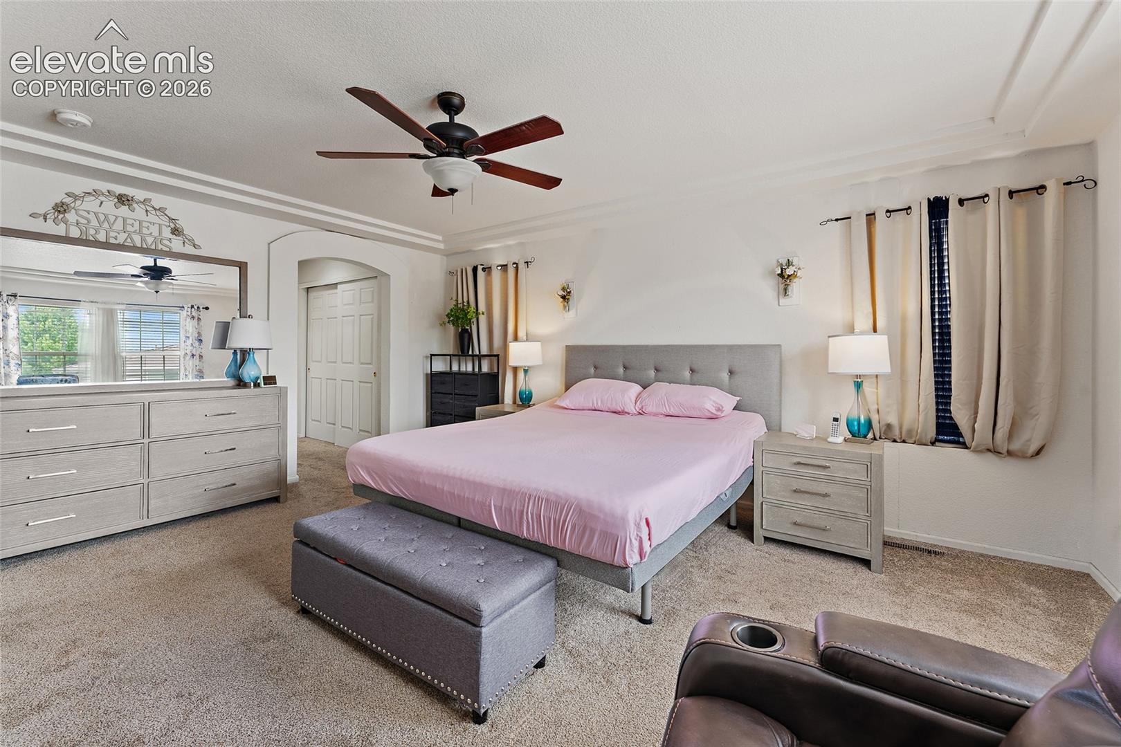 Bedroom featuring crown molding, a central ceiling fan, two wall-mounted light fixtures, and a dual-panel arched doorway